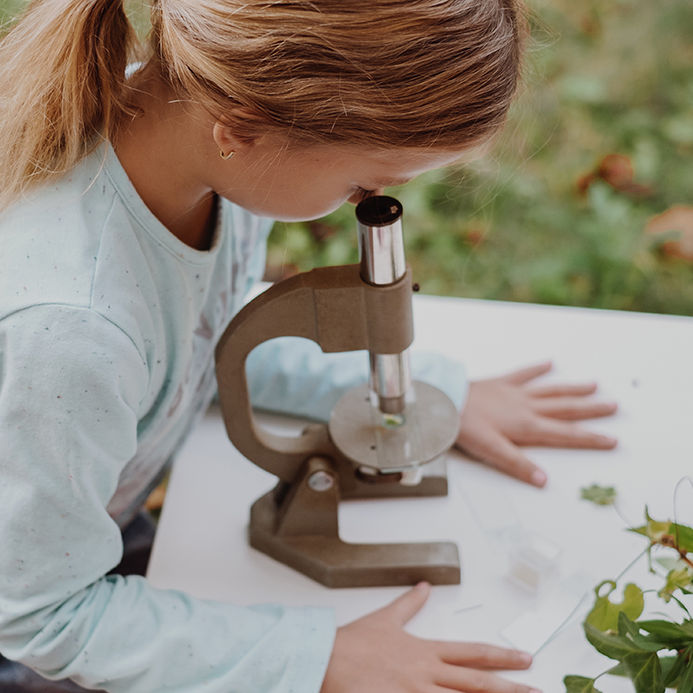 cute little girl is trying to explore the micro world with microscope