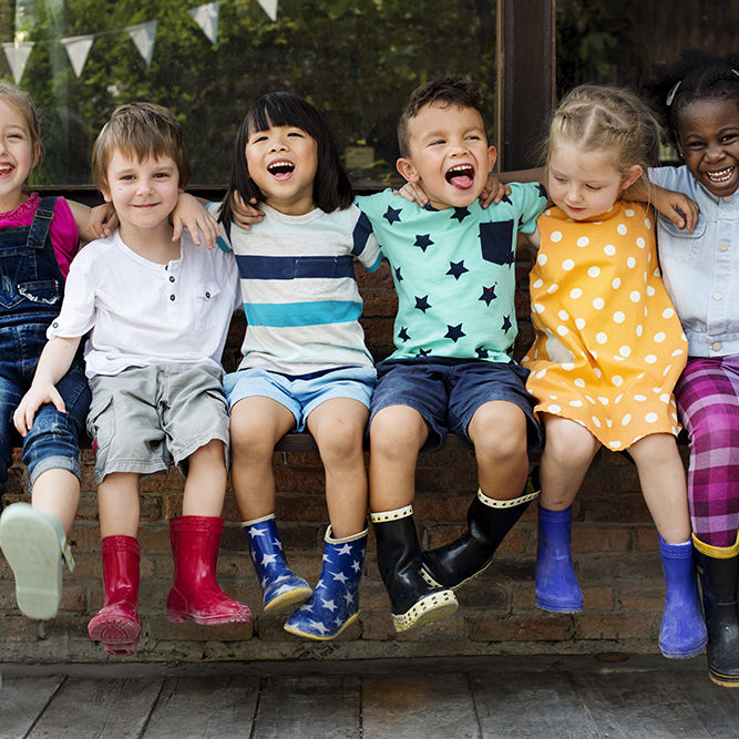 Kindergarten kids friends arm around sitting smiling