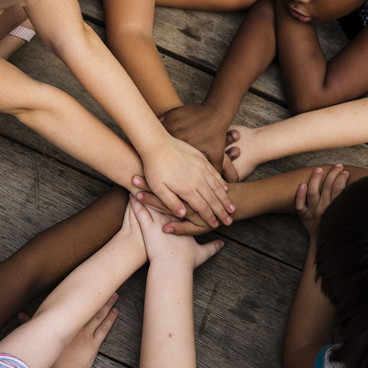 Diverse hands join together on the wooden table