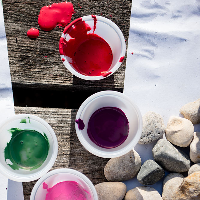 Some cups of paint on a craft table. kids will paint rocks